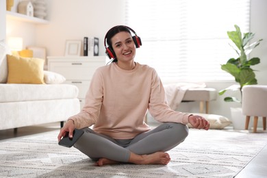 Woman with smartphone meditating on floor at home