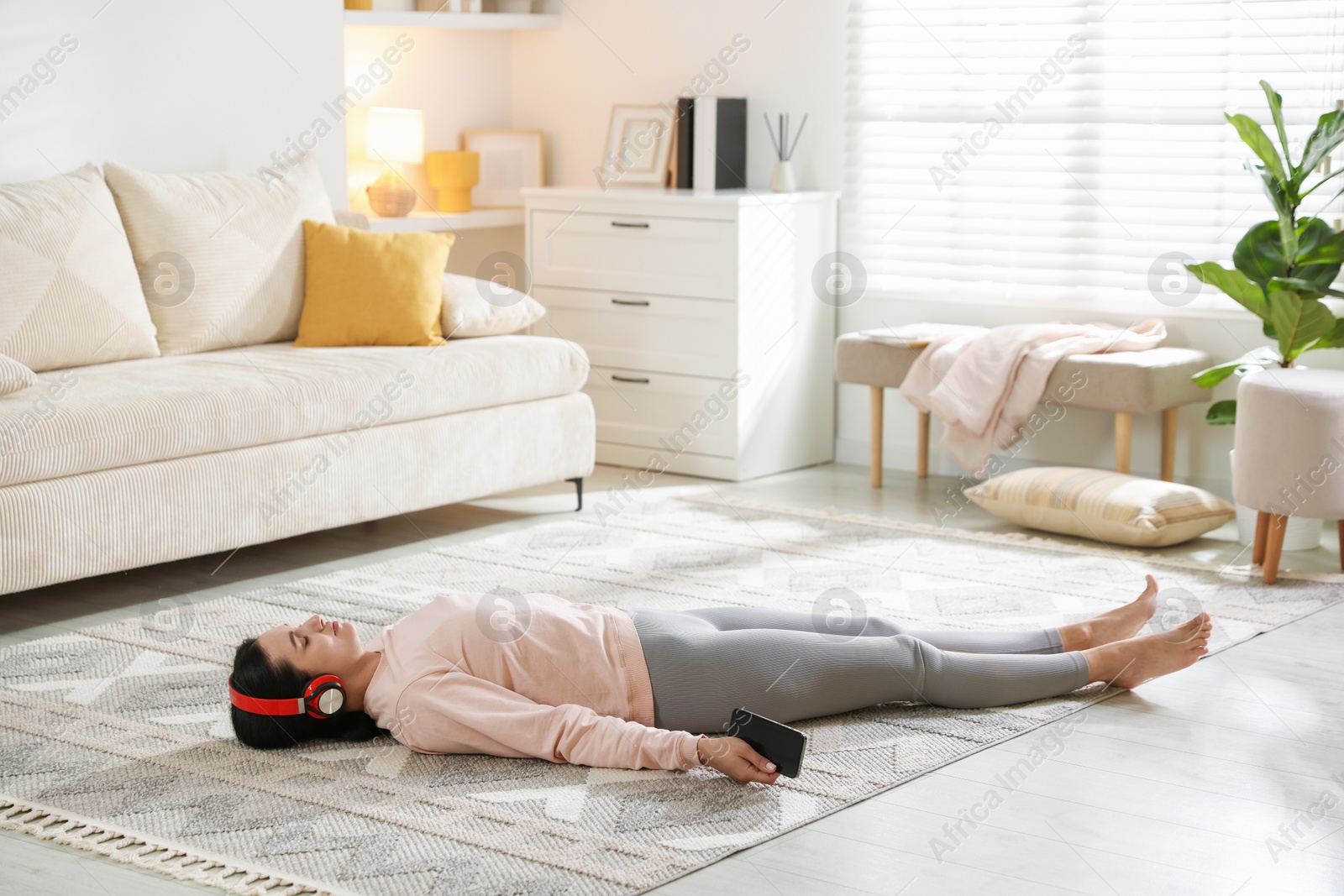 Photo of Woman with smartphone meditating on floor at home