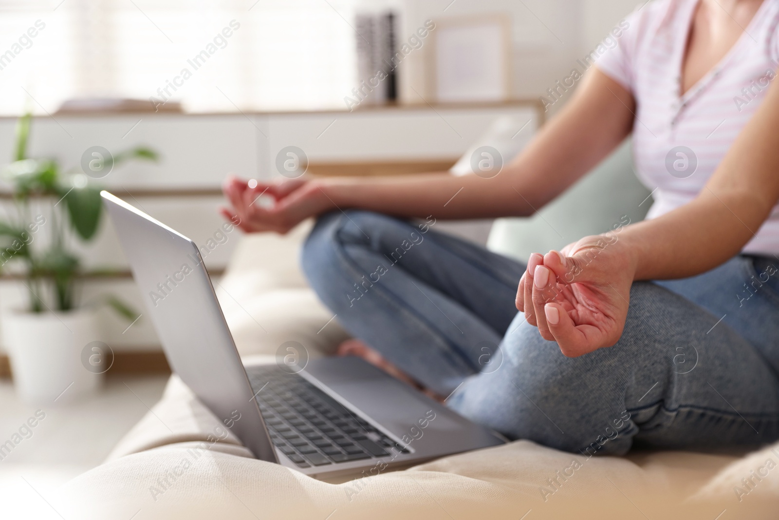 Photo of Woman with laptop meditating on sofa at home, closeup