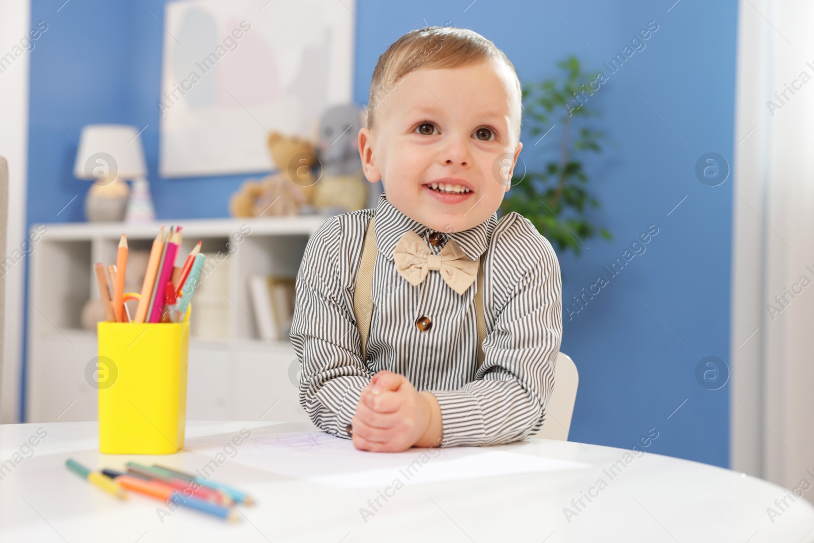 Photo of Little boy with colorful pencils at table indoors