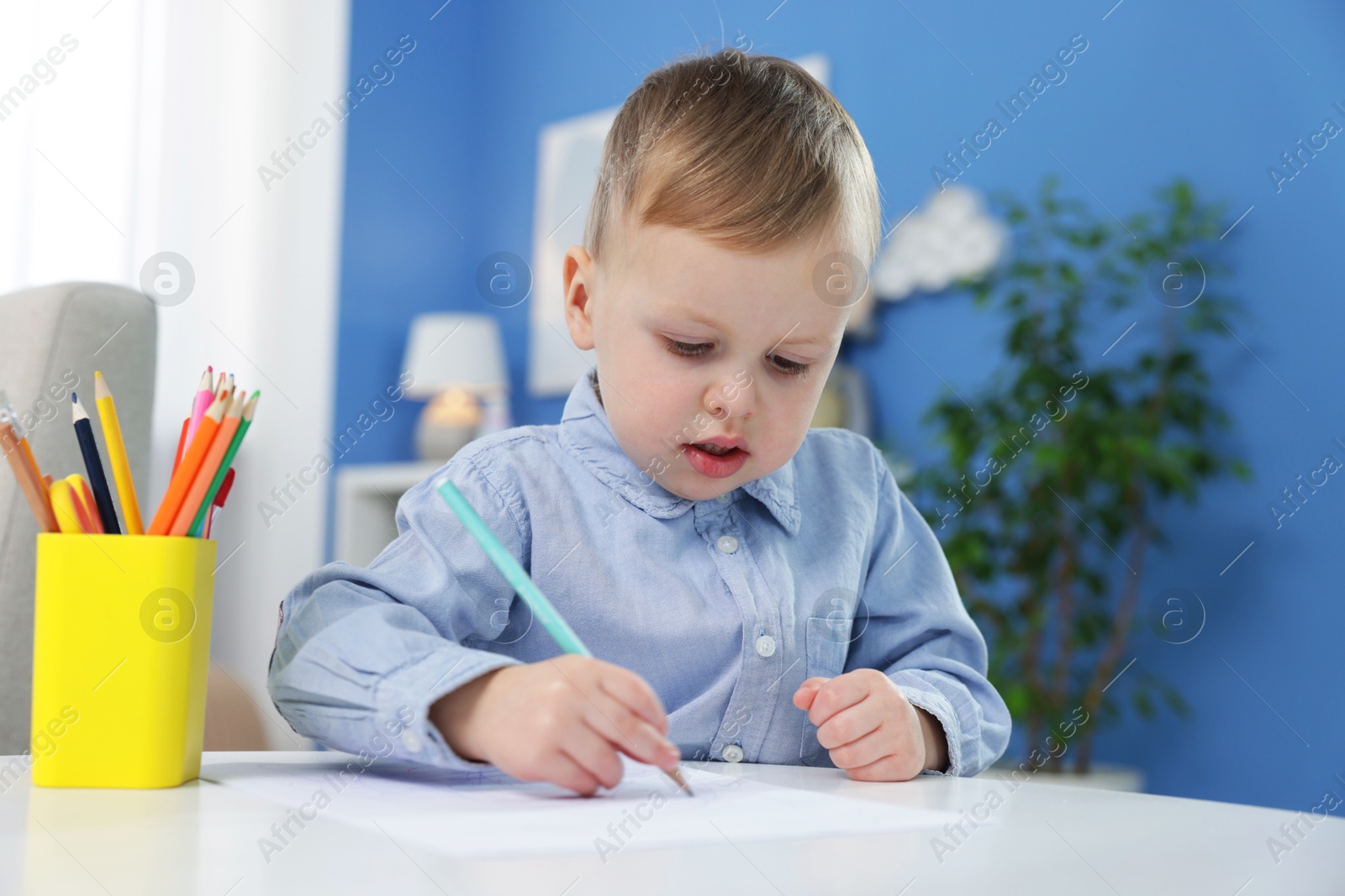 Photo of Little boy with colorful pencils at table indoors