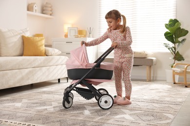 Cute little girl with doll stroller at home