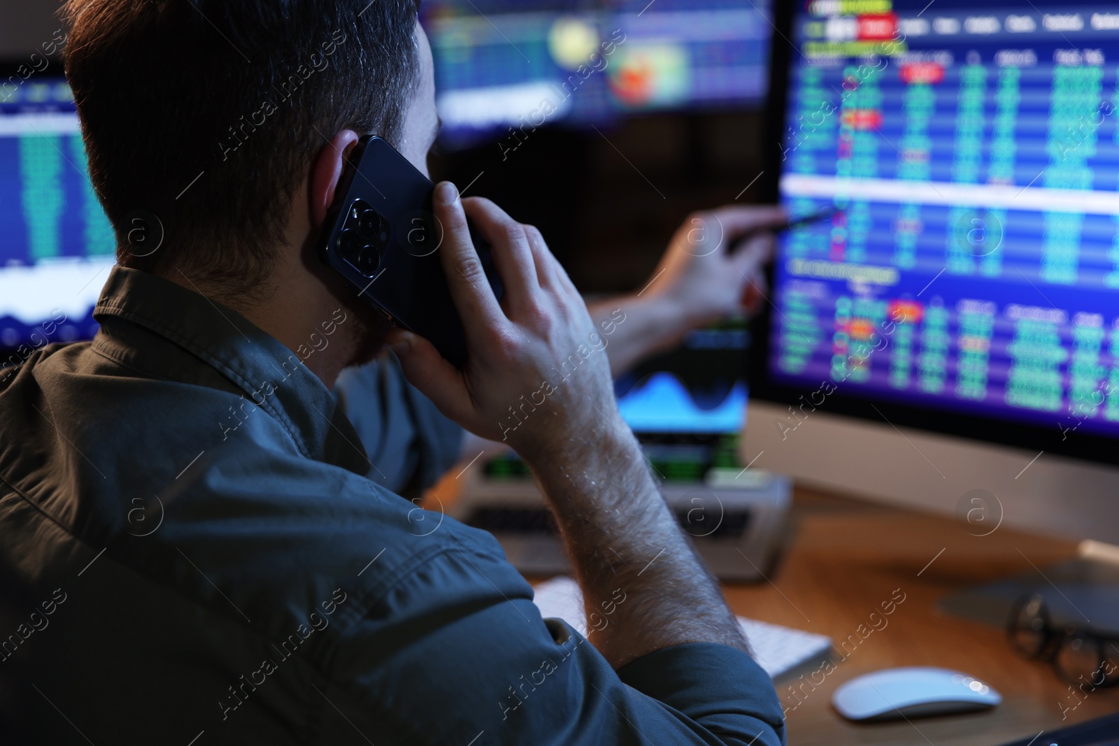 Photo of Financial trading specialist talking on phone in office at night