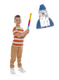 Happy boy breaking rocket shaped pinata with stick on white background