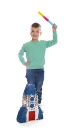 Happy boy with rocket shaped pinata and stick on white background