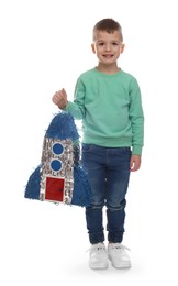 Happy boy with rocket shaped pinata on white background