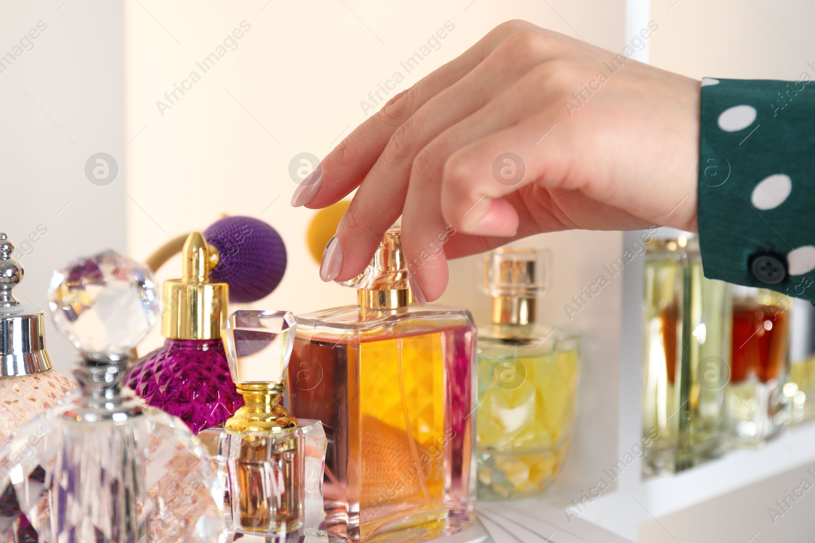 Photo of Woman taking bottle of perfume from shelf in store, closeup