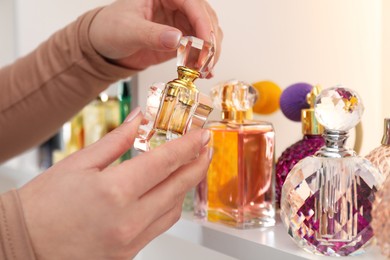 Woman taking bottle of perfume from shelf in store, closeup