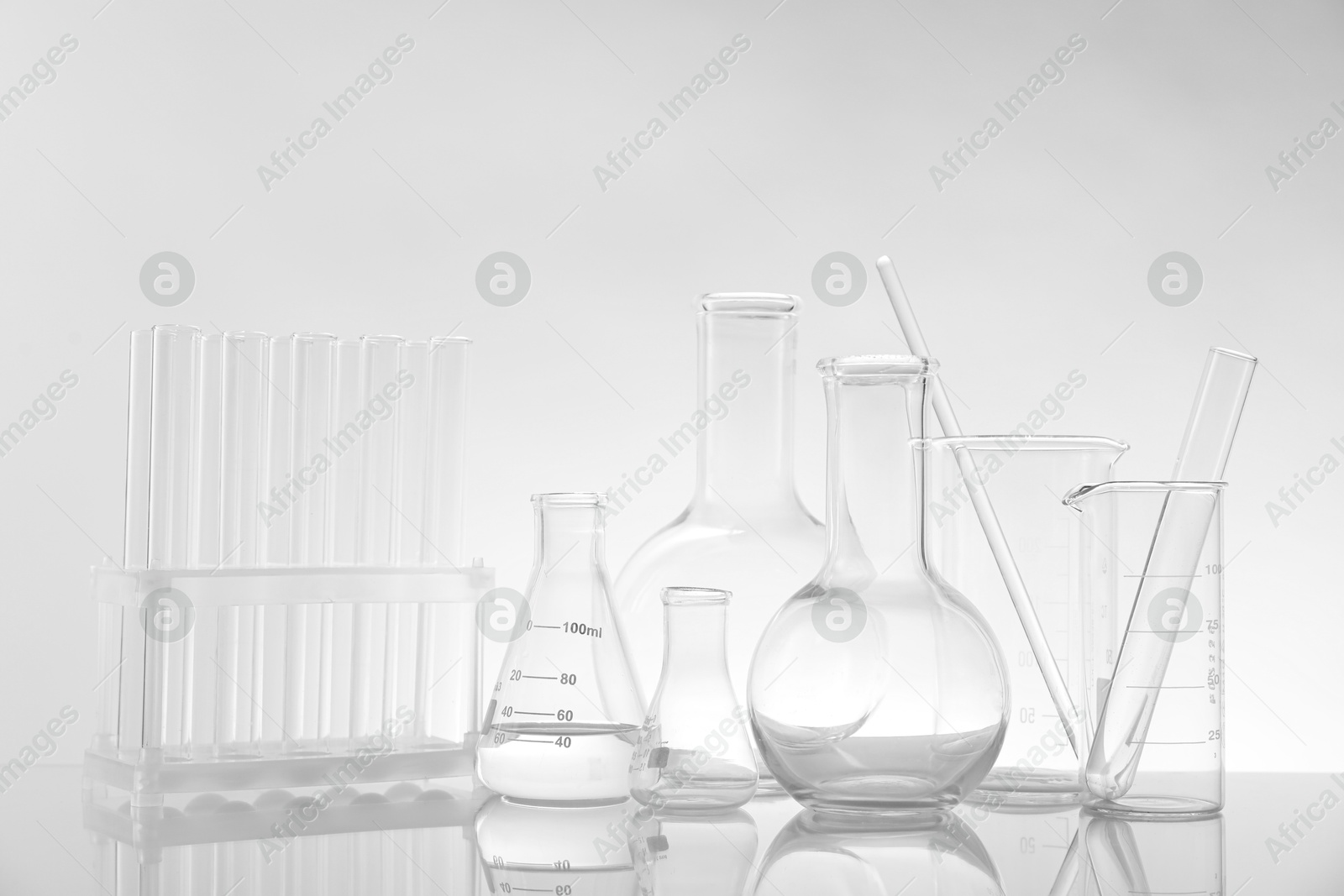 Photo of Laboratory glassware on mirror surface against light background