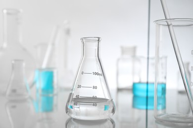 Laboratory glassware on mirror surface against light background