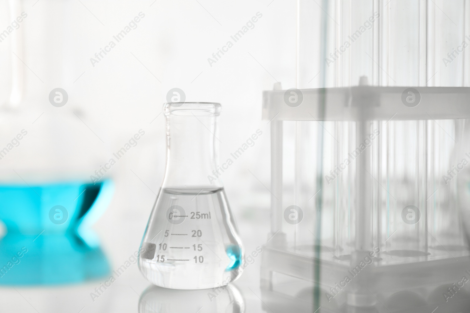 Photo of Laboratory glassware on mirror surface against light background