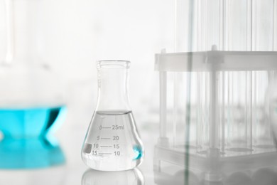 Laboratory glassware on mirror surface against light background