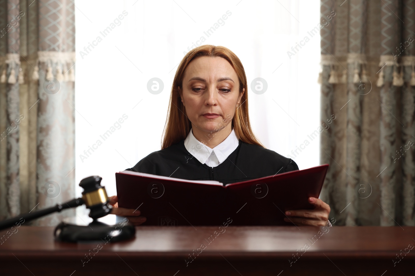 Photo of Judge with folder of documents at wooden table in courtroom