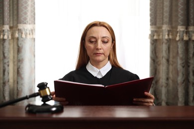 Judge with folder of documents at wooden table in courtroom