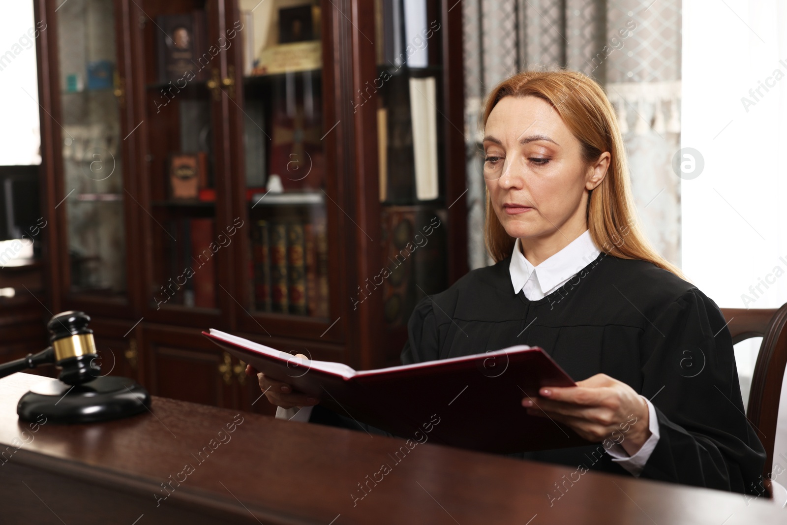 Photo of Judge with folder of documents at wooden table in courtroom