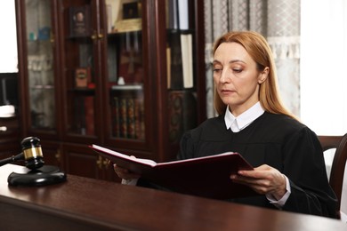 Judge with folder of documents at wooden table in courtroom