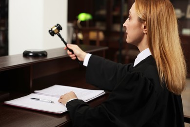 Judge striking gavel at wooden table in courtroom