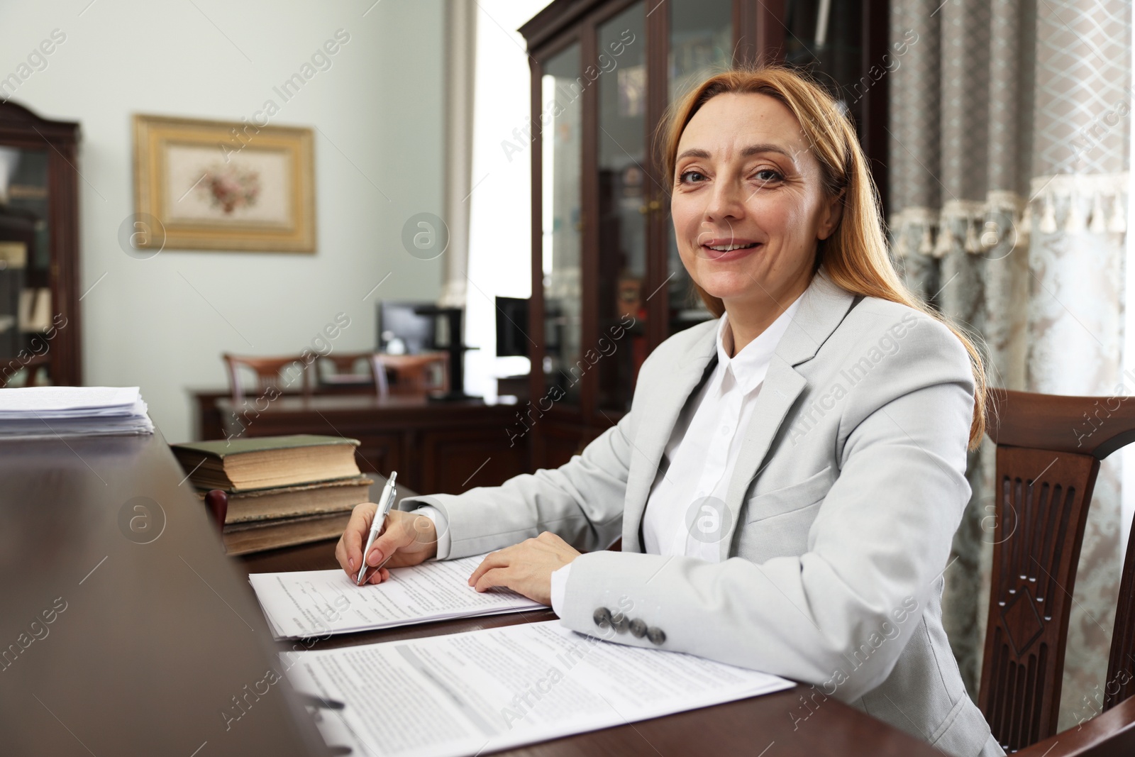 Photo of Smiling notary signing document at table in office