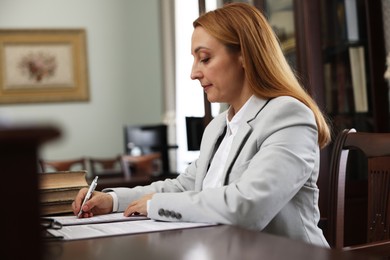 Notary signing document at table in office