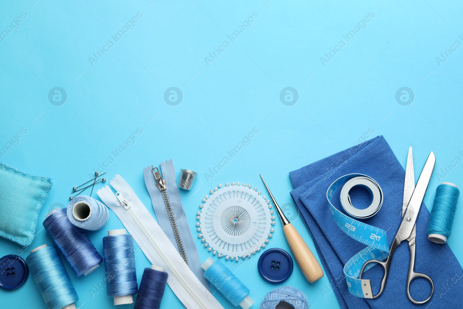 Photo of Different sewing supplies on light blue background, flat lay. Space for text