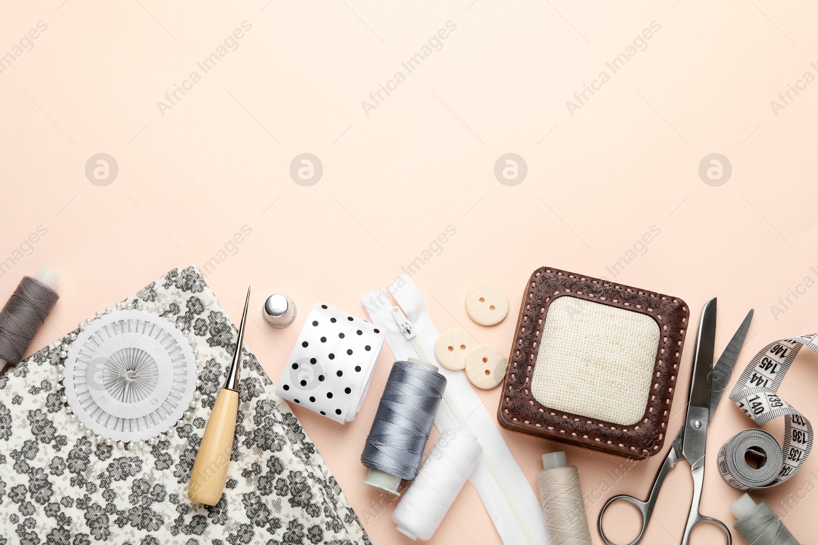 Photo of Different sewing supplies on light pink background, flat lay. Space for text