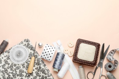 Photo of Different sewing supplies on light pink background, flat lay. Space for text