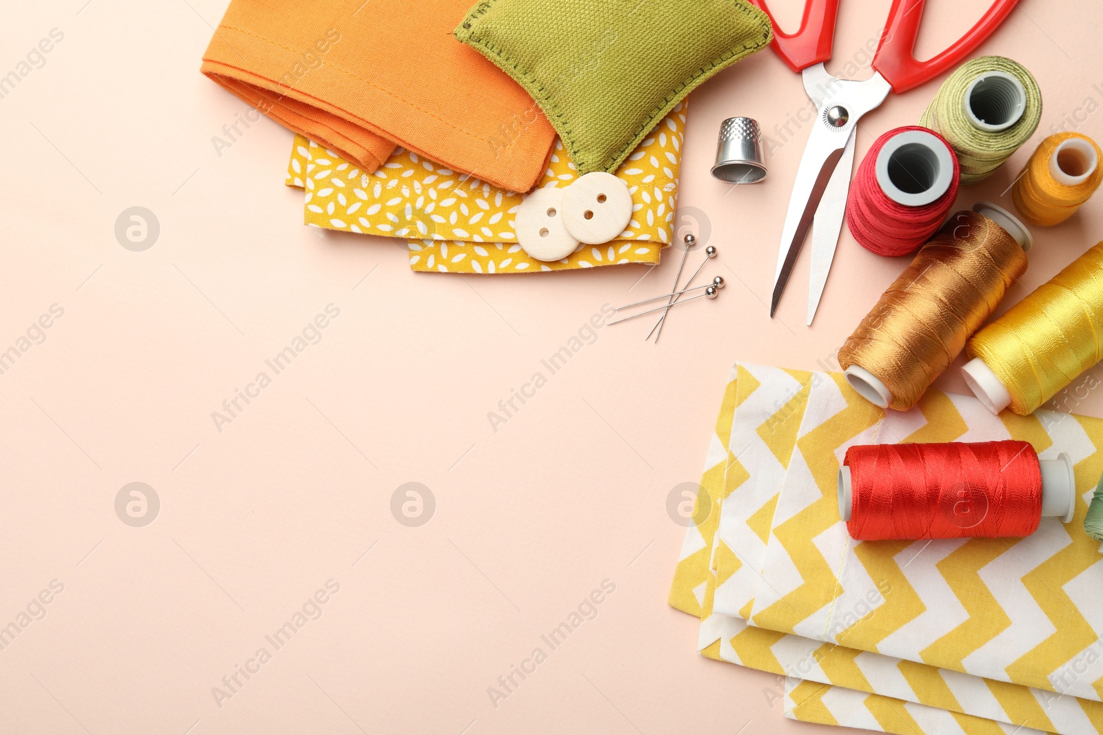 Photo of Different sewing supplies on light pink background, flat lay. Space for text