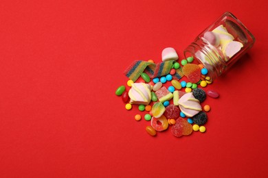 Different delicious candies and marshmallows on red background, flat lay. Space for text