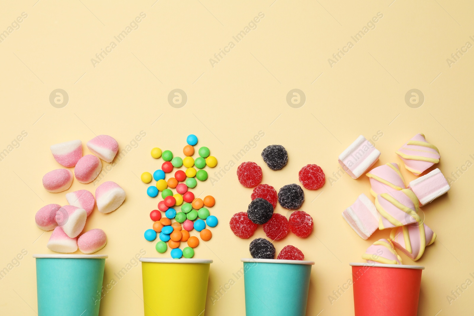 Photo of Different delicious candies and marshmallows on beige background, flat lay. Space for text