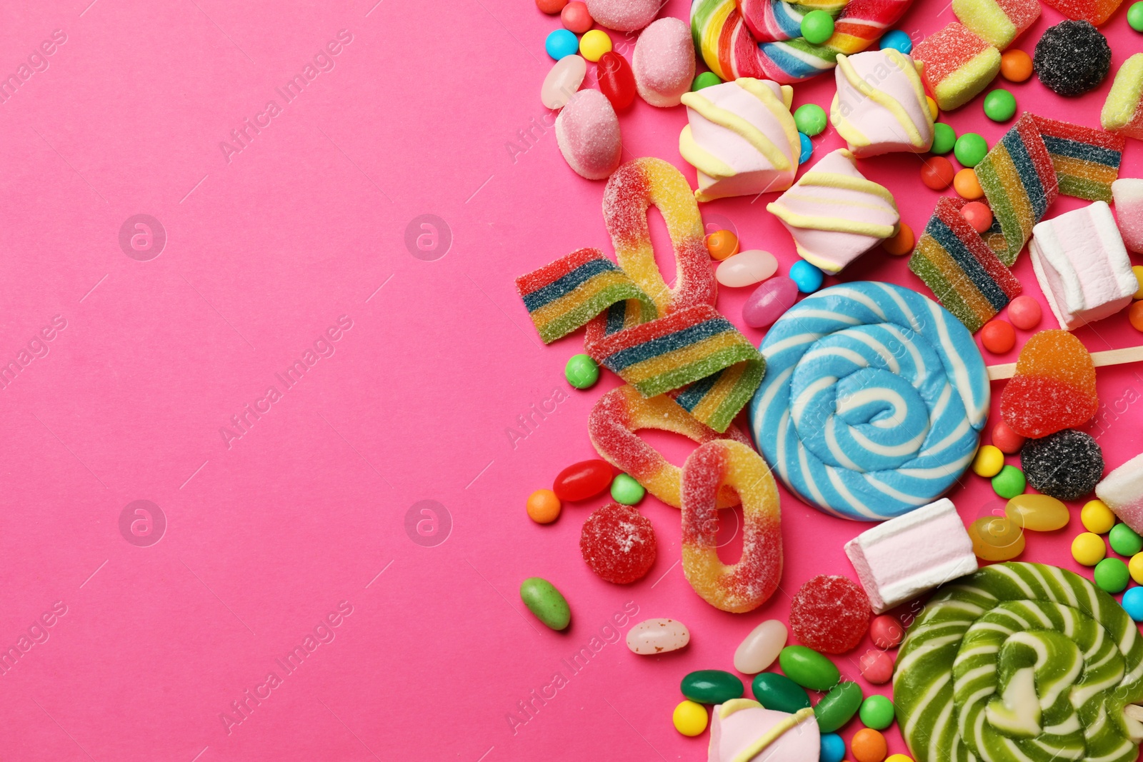 Photo of Different delicious candies and marshmallows on pink background, flat lay. Space for text