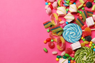 Different delicious candies and marshmallows on pink background, flat lay. Space for text