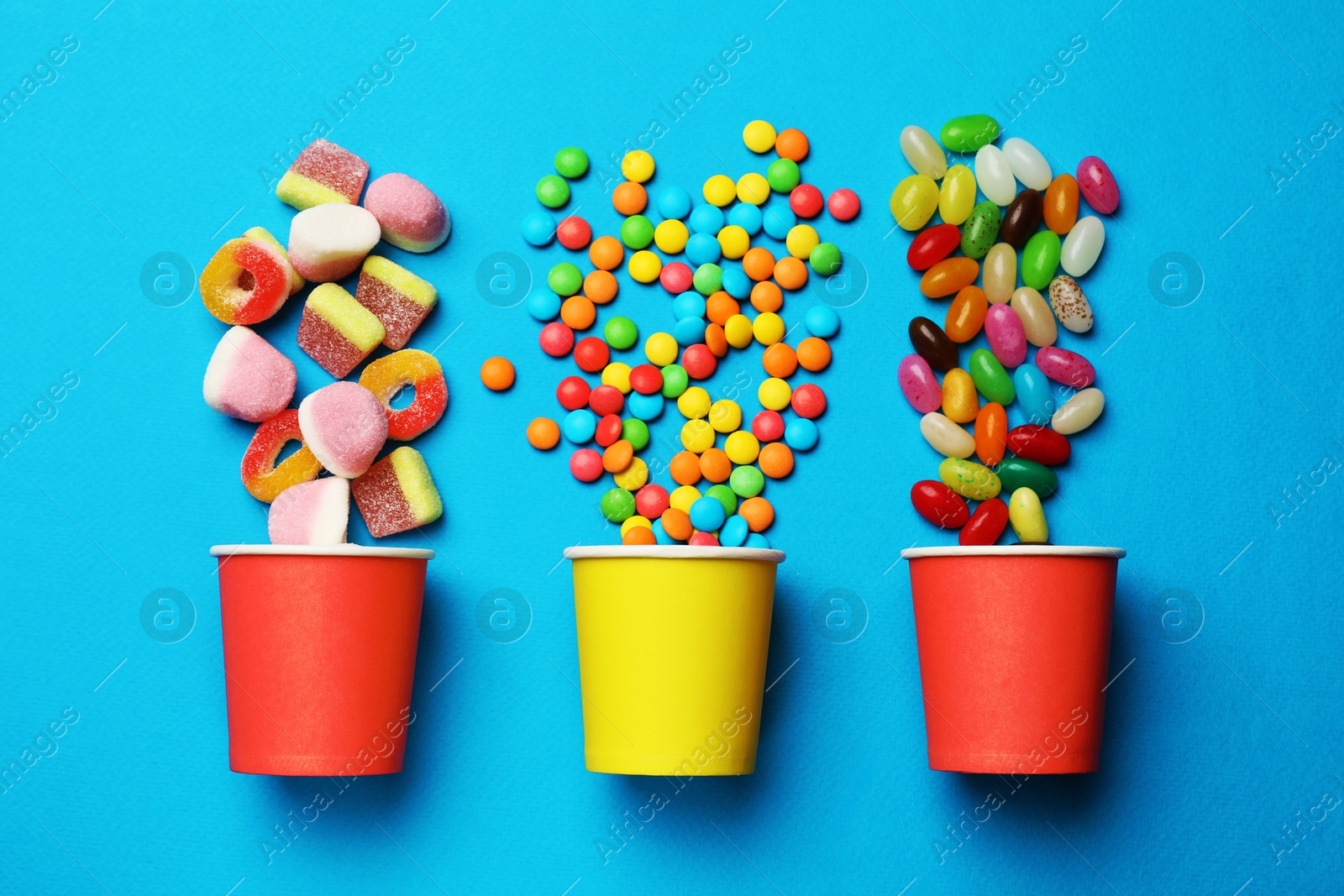 Photo of Different delicious candies on blue background, flat lay