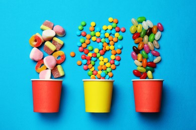 Photo of Different delicious candies on blue background, flat lay