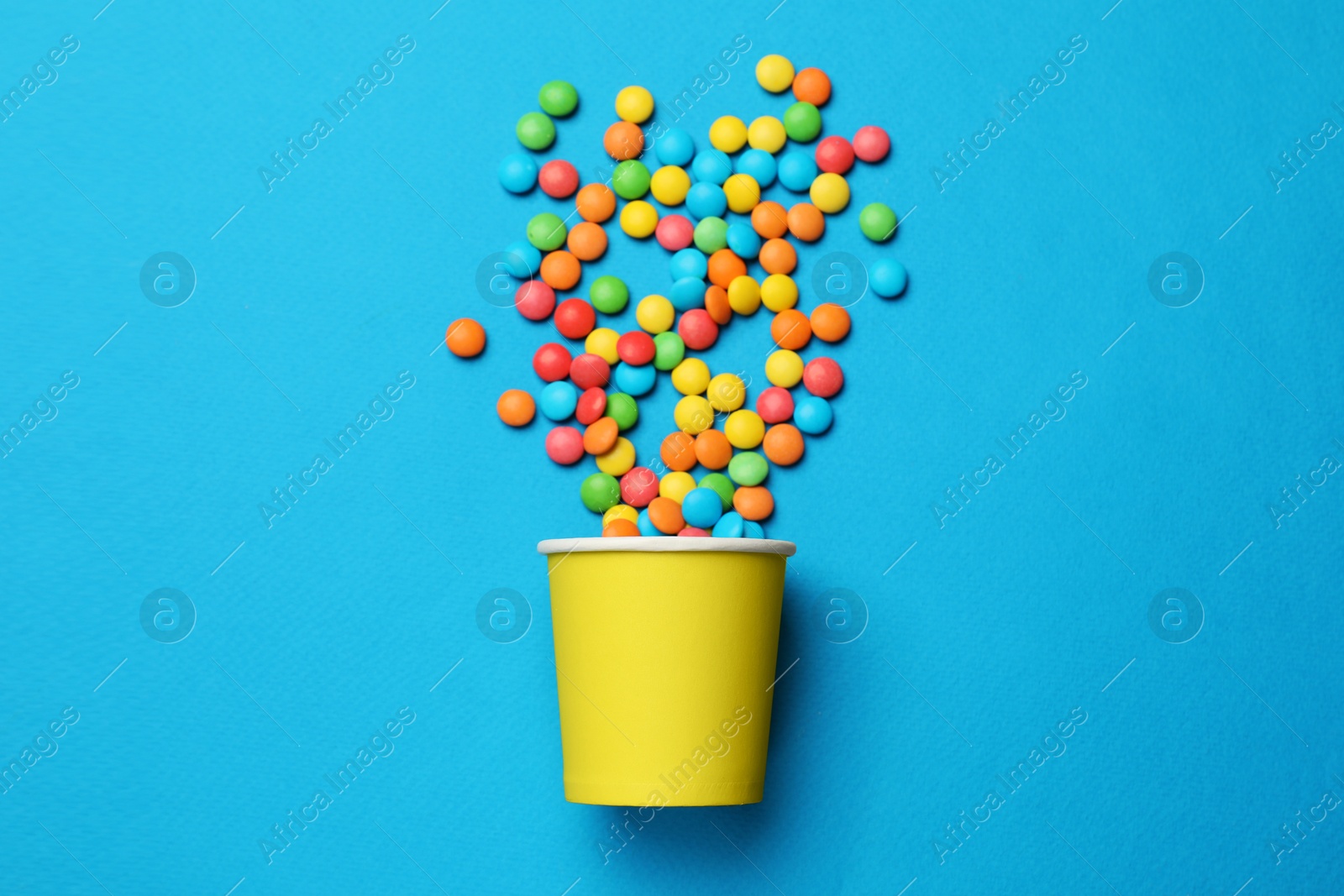 Photo of Colorful sugar coated dragee candies on blue background, top view