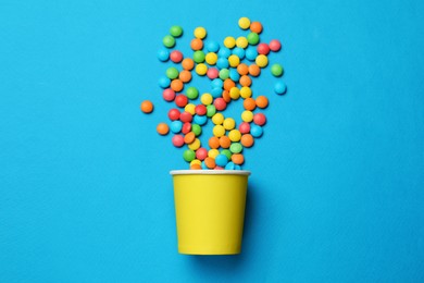 Photo of Colorful sugar coated dragee candies on blue background, top view