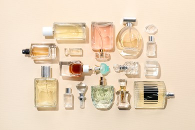 Photo of Bottles of various perfumes on beige background, flat lay