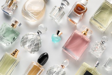 Photo of Bottles of various perfumes on light background, flat lay
