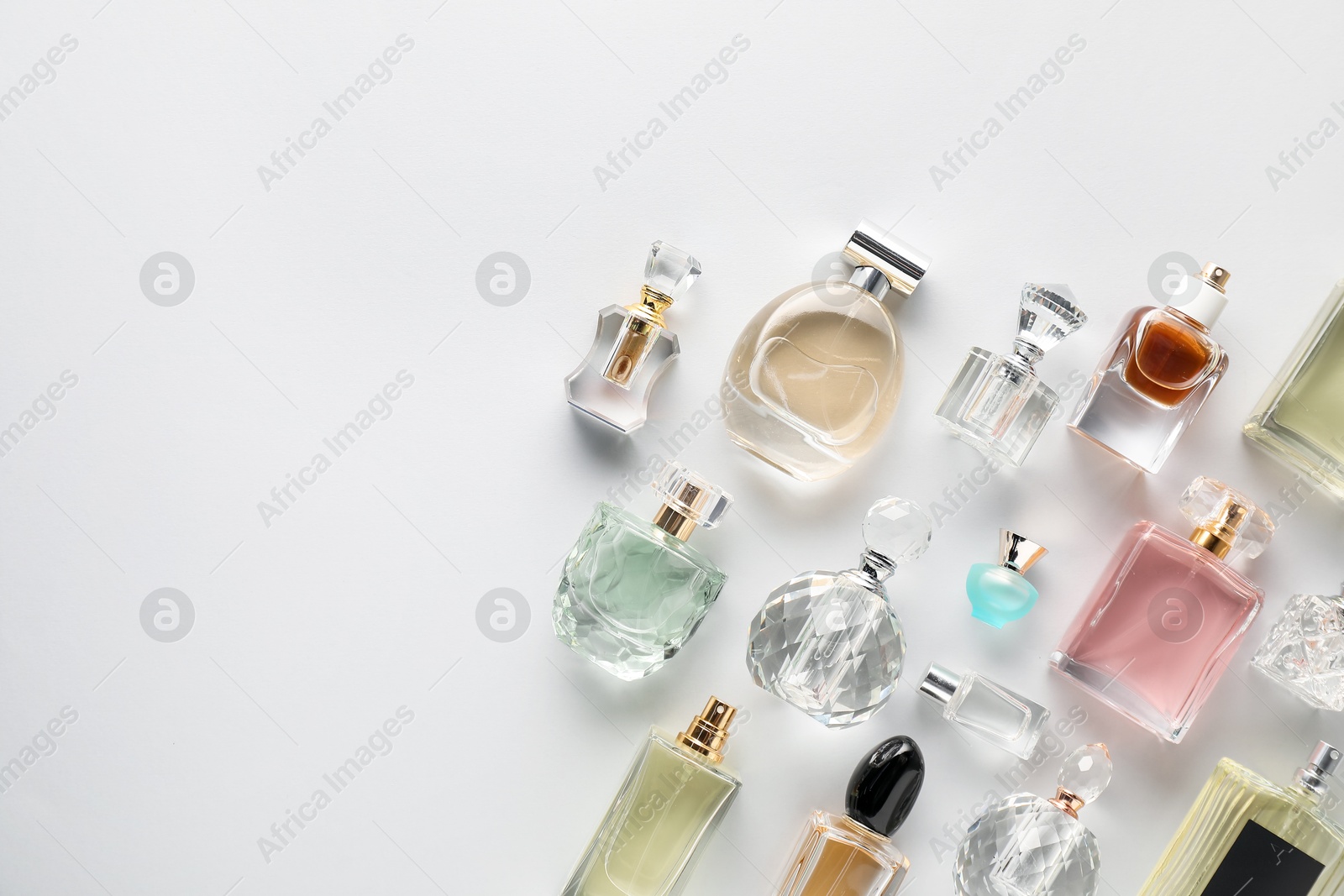 Bottles of various perfumes on light background, flat lay. Space for text Photo of Bottles of various perfumes on light background, flat lay. Space for text