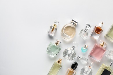 Photo of Bottles of various perfumes on light background, flat lay. Space for text