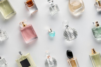 Photo of Bottles of various perfumes on light background, flat lay