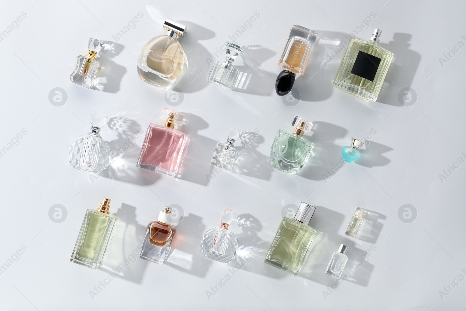 Bottles of various perfumes on light background, flat lay Photo of Bottles of various perfumes on light background, flat lay