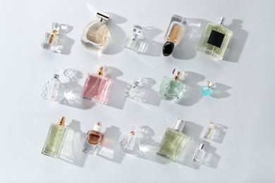 Photo of Bottles of various perfumes on light background, flat lay