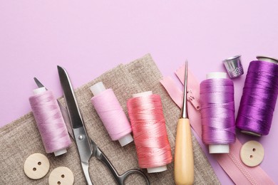 Photo of Different sewing supplies on lilac background, flat lay. Space for text