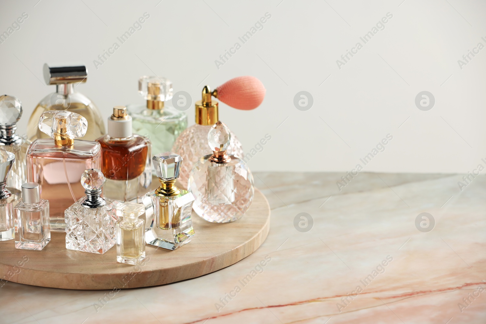 Different luxury perfumes on color marble table, space for text Photo of Different luxury perfumes on color marble table, space for text