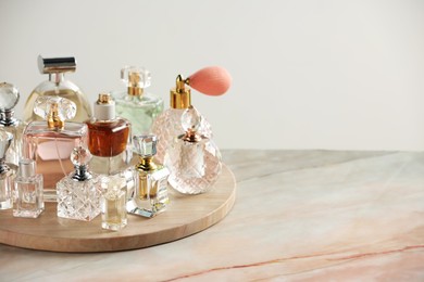 Photo of Different luxury perfumes on color marble table, space for text