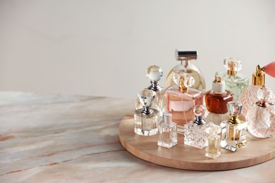 Photo of Different luxury perfumes on color marble table, space for text