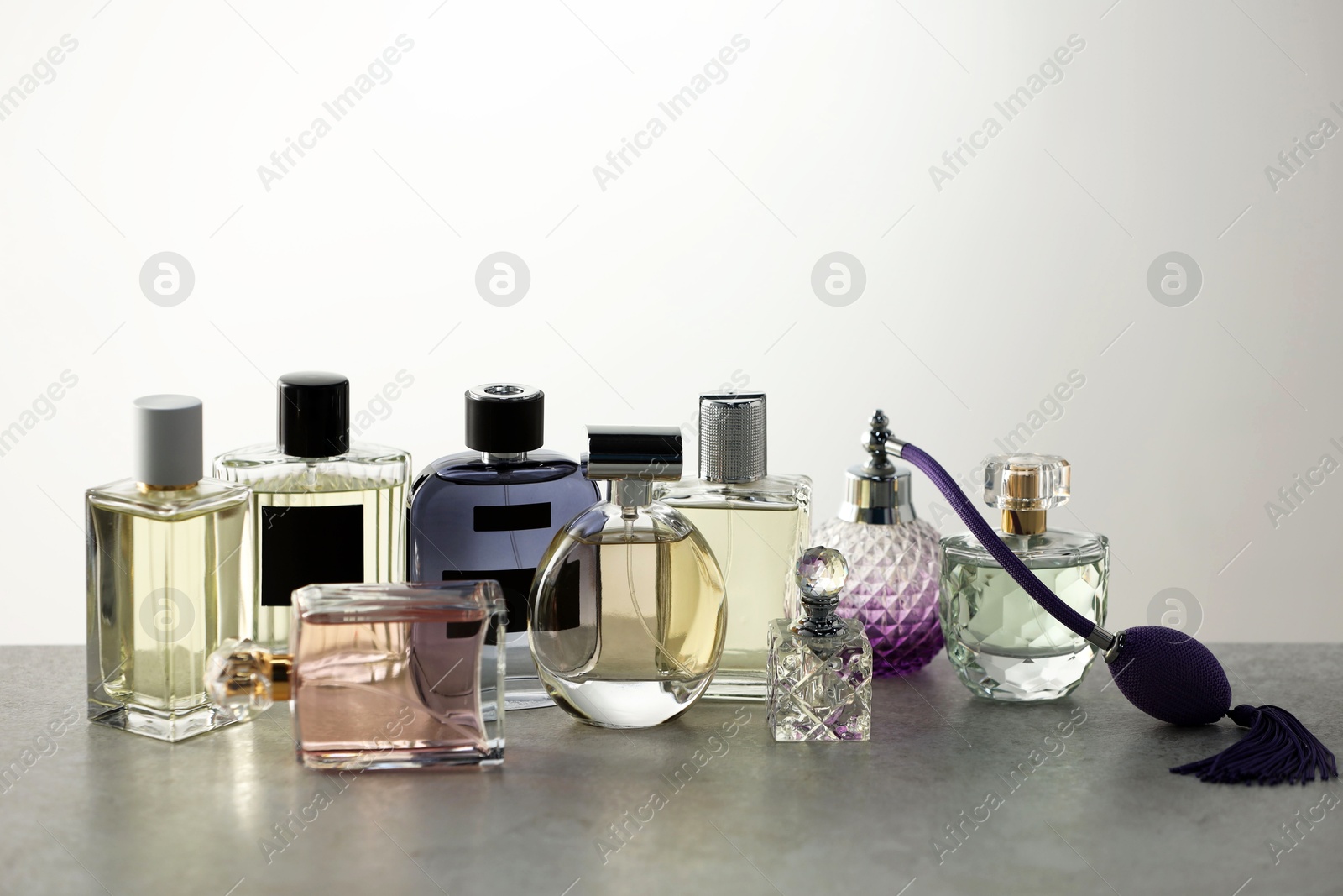 Many different luxury perfumes on grey table Photo of Many different luxury perfumes on grey table