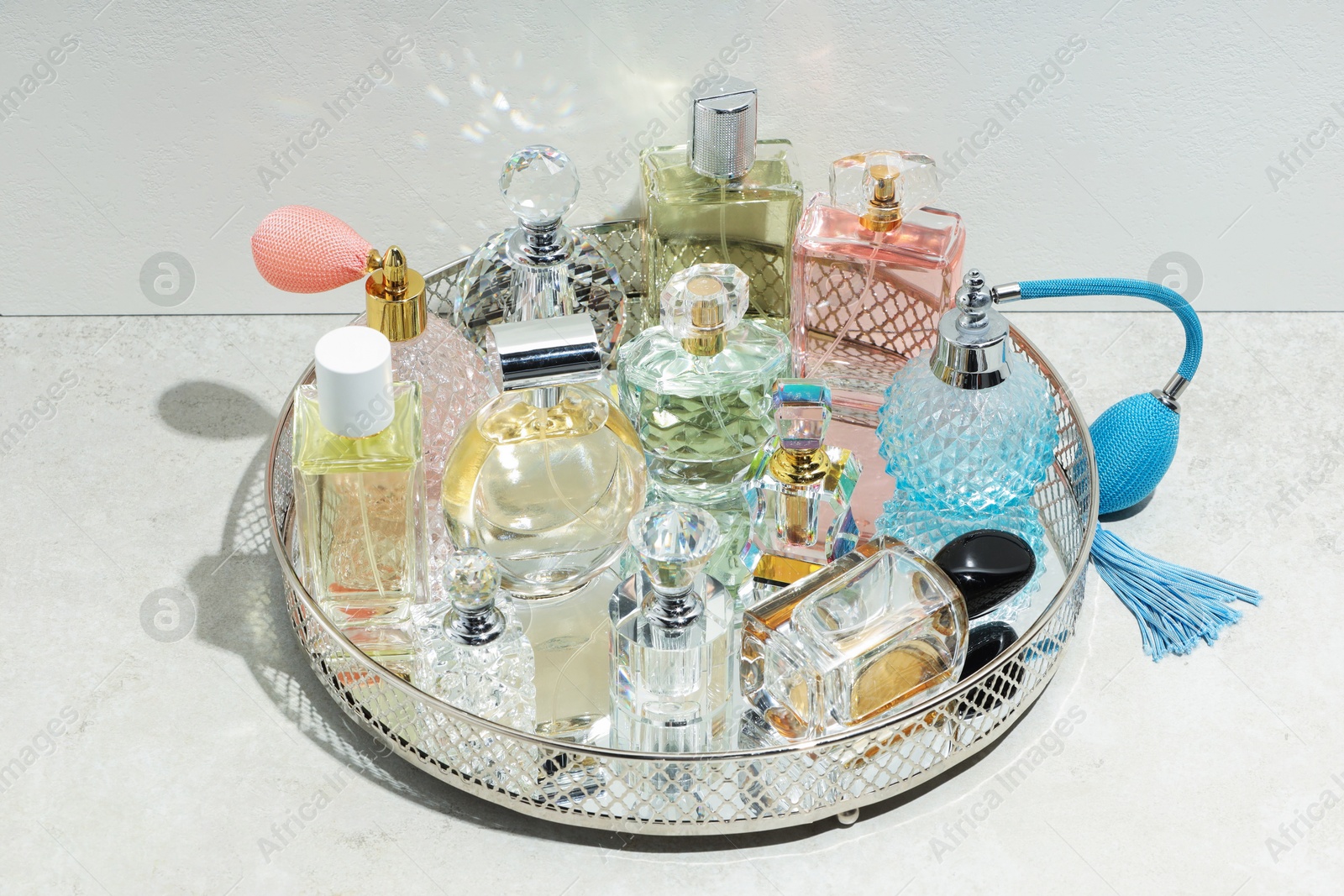 Different luxury perfumes and accessories on light textured table Photo of Different luxury perfumes and accessories on light textured table