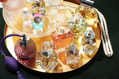 Photo of Different luxury perfumes and accessories on green pouf, above view