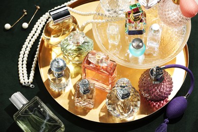 Photo of Different luxury perfumes and accessories on green pouf, above view